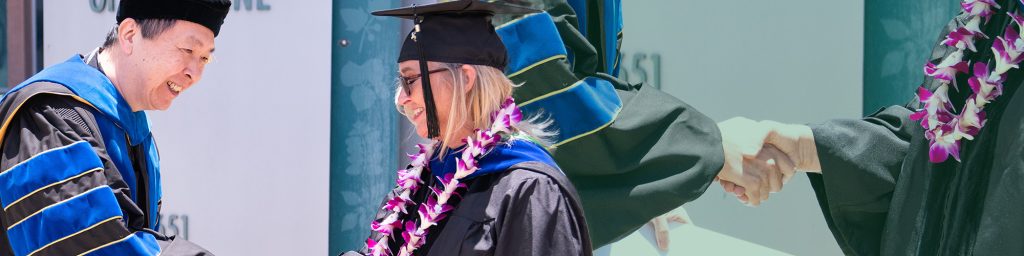 Graduate accepts diploma from faculty member.